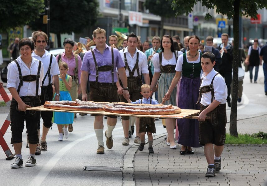 Zwei starke Burschn tragen die größte Brezen zum Wörgler Brezensuppenfest  ©Dabernig Hannes/Kitzbüheler Alpen