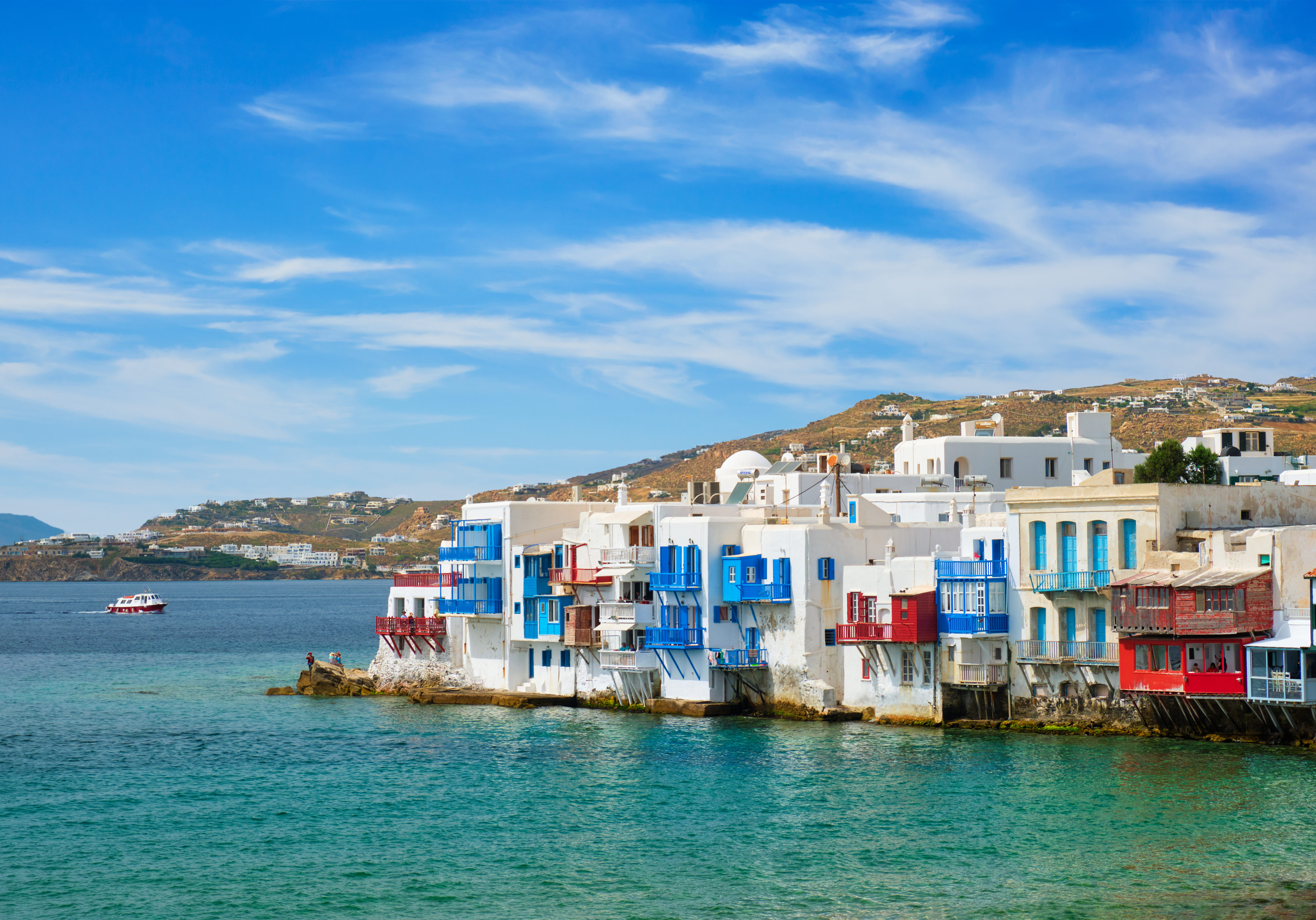 Scenic Little Venice houses in Chora Mykonos town with yacht and cruise ship. Mykonos island, Greecer